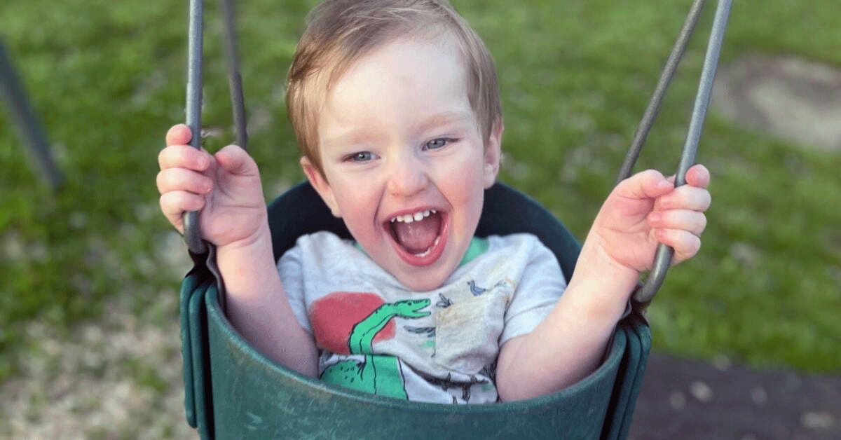 A very happy toddler on a bucket swing.
